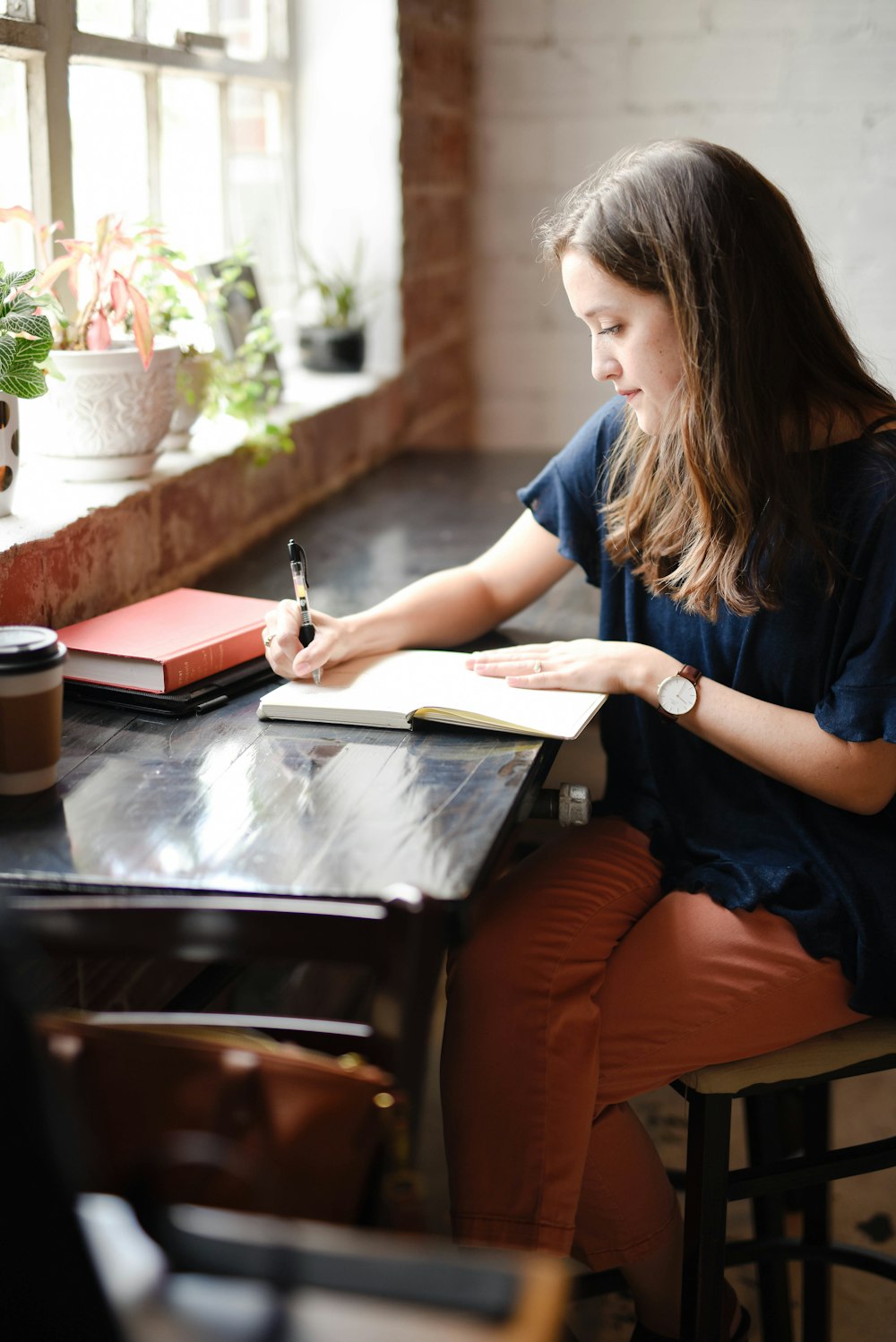 Woman journaling by a sunlit window, a reflective daily habit